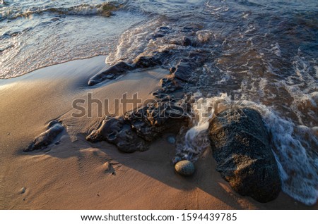 A small wave laps shorline rocks and sand on the Hurricane River Beach, on the Lake Superior shore, Pictured Rocks National Lakeshore, Alger County, Michigan 