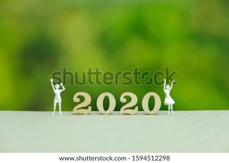 Miniature people - boy and girl with 2020 wooden number. Celebrating new year party