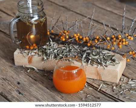 Orange jam from sea buckthorn berries. Tea from dried leaves and berries of sea buckthorn for use in folk medicine on an ancient wooden table.