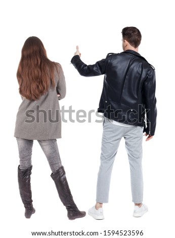 Back view of couple couple in winter jackets showing thumbs up. beautiful friendly girl and guy together. Rear view people collection. backside view of person. Isolated over white background.