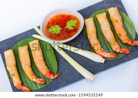Picture of Thai food Fried shrimp spring rolls are shrimp prawns wrapped in cassava chips and deep fried, eaten with sweet sauce, placed on a salad in a stone tray.