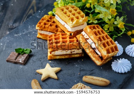 Near the spread of snow little meringue On graphite colors of flat stone meringue tiles there are shaped cookies, of different kinds, peaks of gentle beze, chocolate tiles, large Vienna waffles 