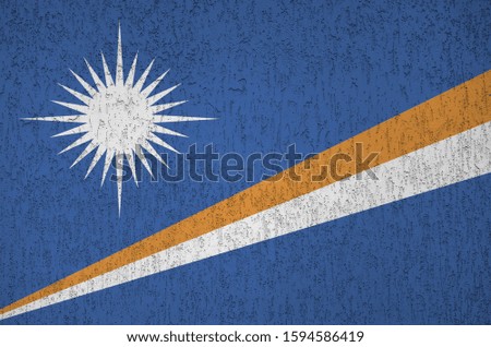 Marshall Islands flag depicted in bright paint colors on old relief plastering wall. Textured banner on rough background