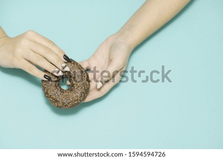 Appetizing donuts with icing on a colored background with female hands with a beautiful manicure. Trend photo