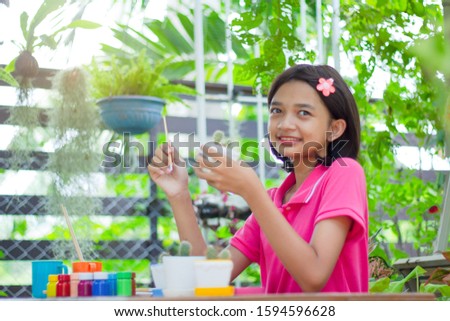 Asia girl painting pot with many color bottle at the garden.