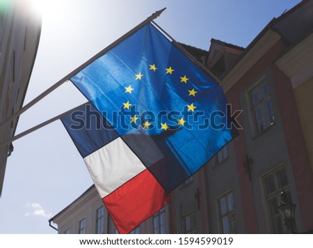 Flags of France and the European Union on the building against the blue sky on a bright Sunny day