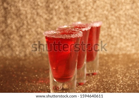 Three glasses with red alcoholic drinks. Background gold shiny
