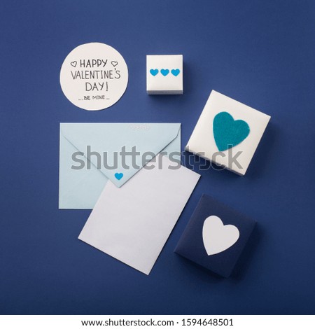Valentines day, birthday, wedding or other holiday composition. Empty card with blue envelope, gifts and hearts. Mockup template. View from above. Blue background