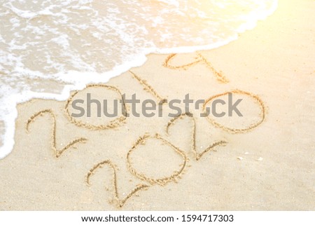 Countdown to the year 2020 or to the new year on the beach sand with waves and sun light. Happy new year concept.