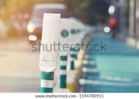 focus bike lane sign pole with green tree and way for bicycle in background with copy space
