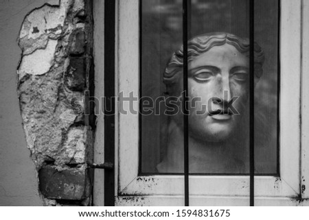 Plaster head of a man. The sculpture outside the window. Iron grate and glass. Screensaver for your desktop 