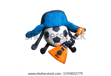 Plasticine soccer ball in russian traditional blue hat with earflaps with orange balalaika isolated on white background