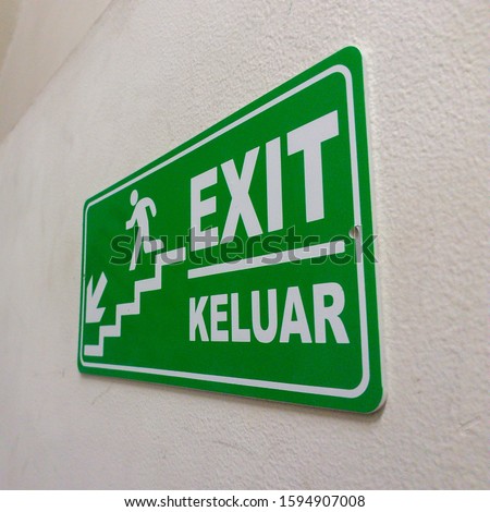Green exit sign plate with a man figure and arrow to go to the downstairs as an instruction for directions in case of an emergency
(Indonesian meaning: exit)
