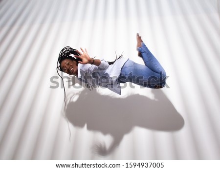 trendy concept, african american woman levitating over light abstract stripy background with a shadow