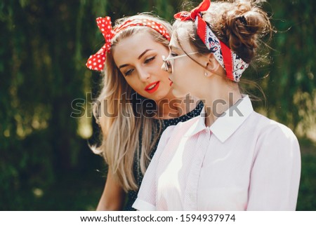 Stylish girls in a retro dress. Vintage ladies in a summer park. Two women have fun