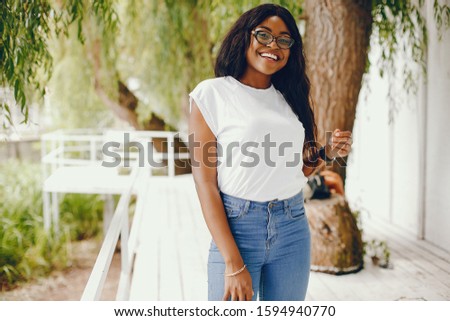 Cute black girl in a park. Lady in a white t-shirt and blue jeans. Woman in a sunglasses