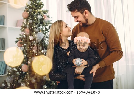 Beautiful mother in a black dress. Family sitting with christmas gifts. Little girl near christmas tree