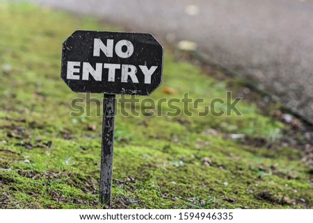 Little old wooden black and white painted NO ENTRY sign on a grass verge.