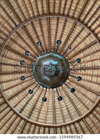 A chandelier hanging under a bamboo thatch roof.