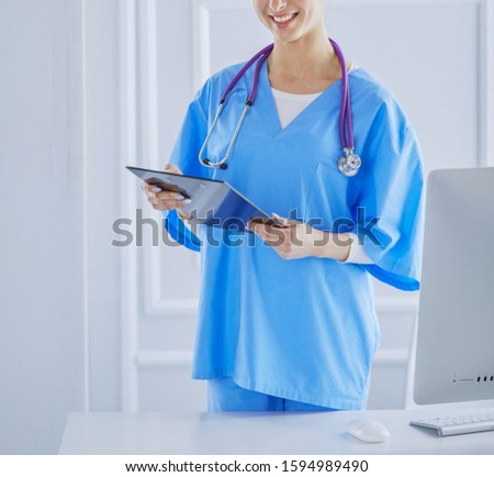 Smiling female doctor with a folder in uniform standing