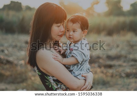 Asian mother holds her daughter in a warm light. , Family Concept