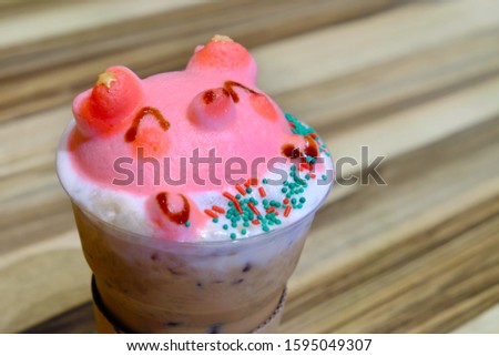 Bubble foam in smiling pink pig head shape over iced coffee