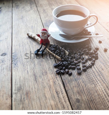 Santa sitting on wooden spoon full of coffee beans with big cup of coffee , good morning concept
