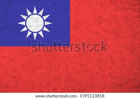 Taiwan flag depicted in bright paint colors on old relief plastering wall. Textured banner on rough background