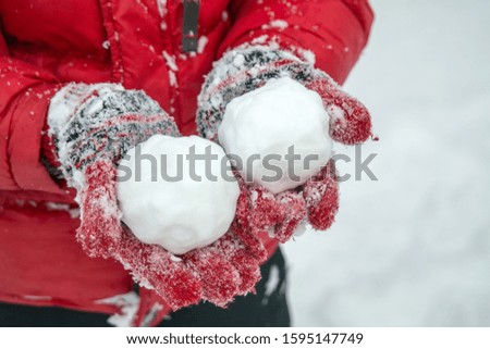 children's hands in mittens hold a snowball.