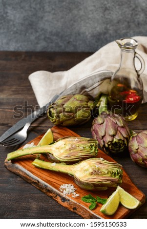 vegan appetizer artichoke with olive oil, mint and lime. Artichoke salad on a wooden board and wooden background.
