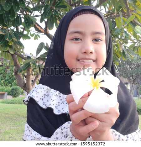 Cute Asian gile muslim on black hijab show white flower in her hand face nice smilling and happy, muslim lifestyle, Islamic concept, happiness idea, portrait image,