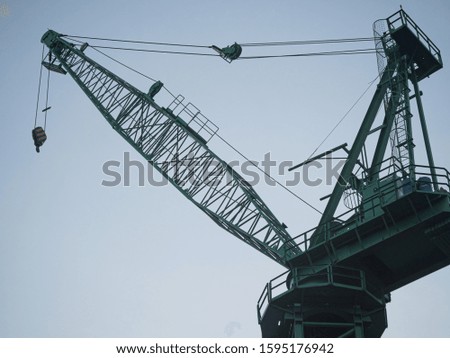 High-rise building crane with a long arrow of green color 