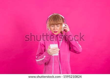 senior woman with mobile phone and headphones isolated on pink background
