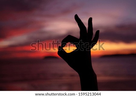One hand operation on sunset background.