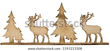 Cut out deer figure made of wood with dark edges and wooden fir trees
