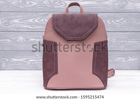 Synthetic leather pink backpack on a wooden background. Eco leather bag.
