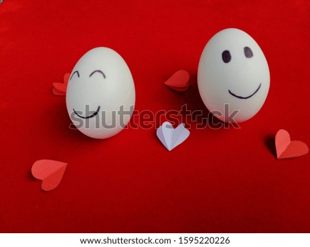 Happy Valentines day. Couple Egg in love with painted smiley in red background

