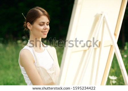 young woman paints a picture in the fresh air
