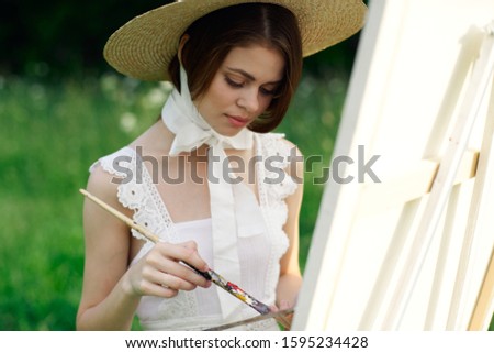 young woman paints a picture in the fresh air