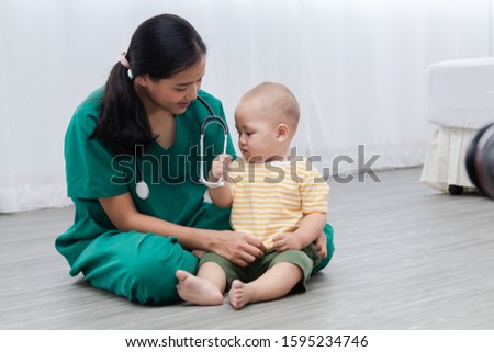 Asian pediatrician doctor woman green uniform hold stethoscope annual check up toddler boy by monitoring heart pulse rate , nurse play with preschool boy during examination, child health care concept