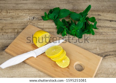 Lemons sliced on a wooden board which stands on a table with mint