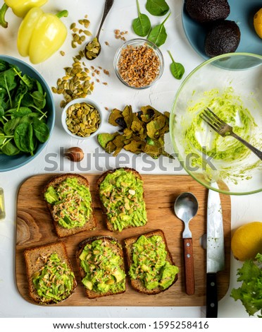 Sandwiches with avocado guacomole with pumpkin seeds and wheat seedlings on a wooden board. Top view