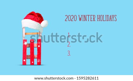 2020. Winter holidays. Sled in a hat of Santa Claus on a blue background. Winter holiday concept. Copy space. New year background.