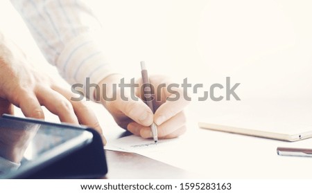 Business meeting. A man signs a contract. Male hand with pen makes notes in office.