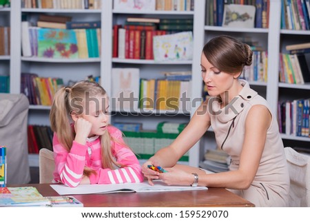Child psychologist with a little girl, a child draws with colored pencils