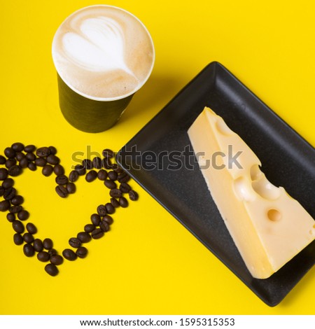 White Cup with coffee on yellow background and coffee beans in heart shape.