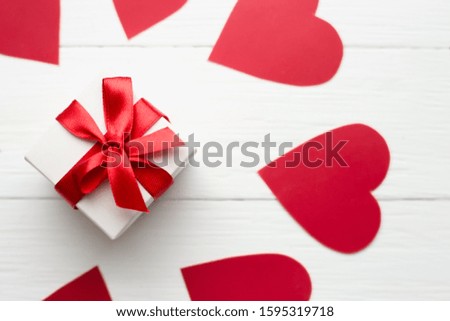 Red hearts with a gift box on a white wooden background. Happy Valentine's day red hearts on wooden background