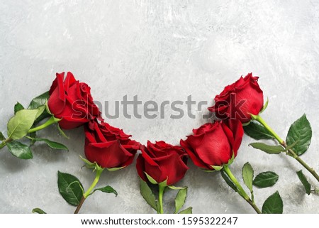Fresh red roses frame on a gray concrete background. Top view, flat lay