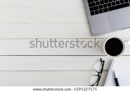 Flat lay, top view wooden office desk. Workspace with blank notebook, laptop, eye glasses, pen, coffee cup office supplies with coppy space on white wood table background