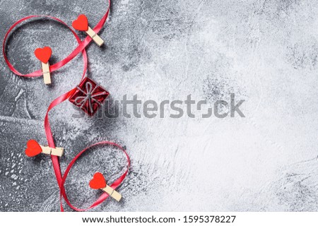 The concept of Valentine day. Gift box with red ribbon and hearts. Gray background. Top view. Space for text